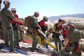 rescue team in green clothing on rocky slope