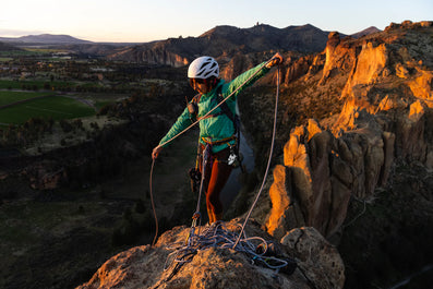 Person rock climbing on a cliff with a scenic landscape in the background