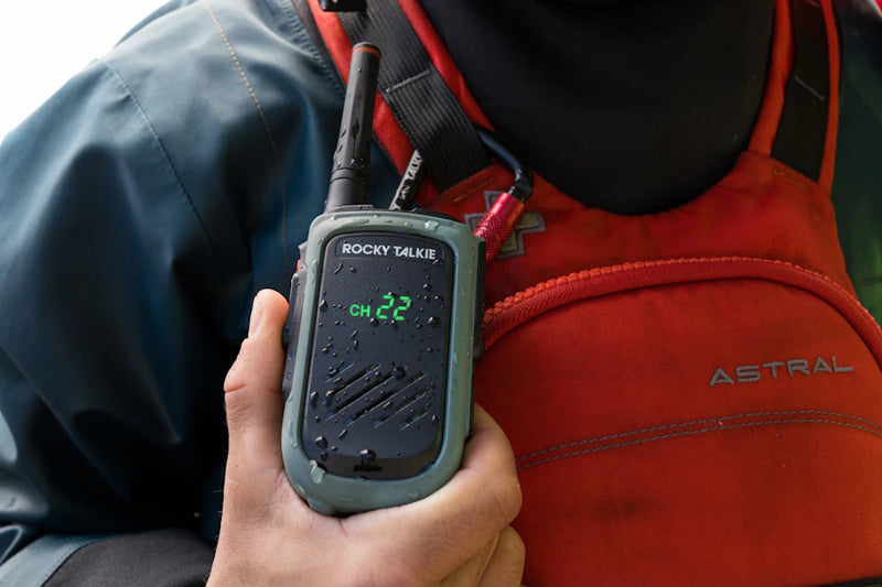 Person holding a Rocky Talkie walkie-talkie with a red vest in the background