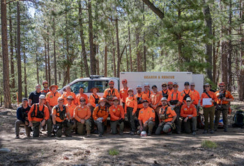rescue team in orange shirts posing in front of white truck in forest