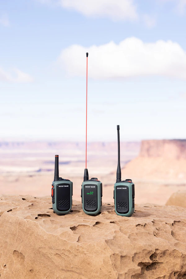 Three walkie-talkies on a rock with a desert landscape in the background