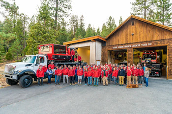 rescue team in red shirts posing for photo in front of barn