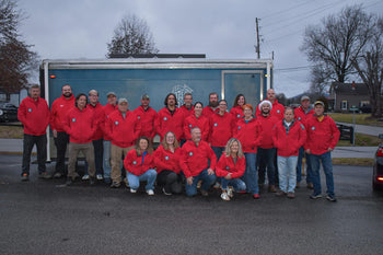 rescue team in red shirts standing in front of grey trailer