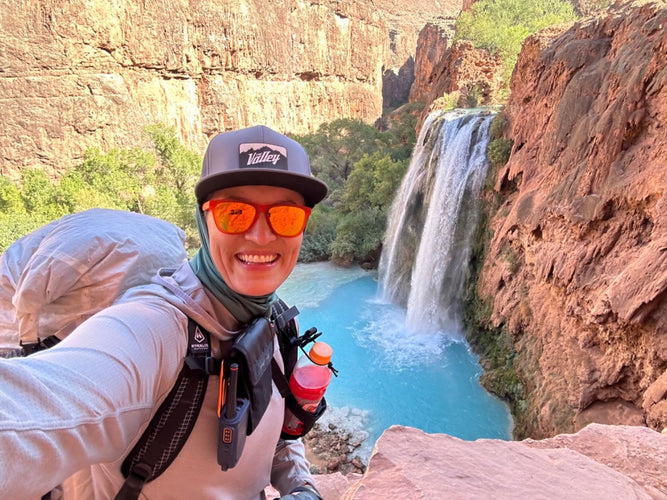 Person taking a selfie with a waterfall and canyon in the background