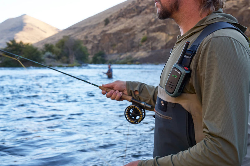 This image shows a person engaged in fly fishing by the riverside.
