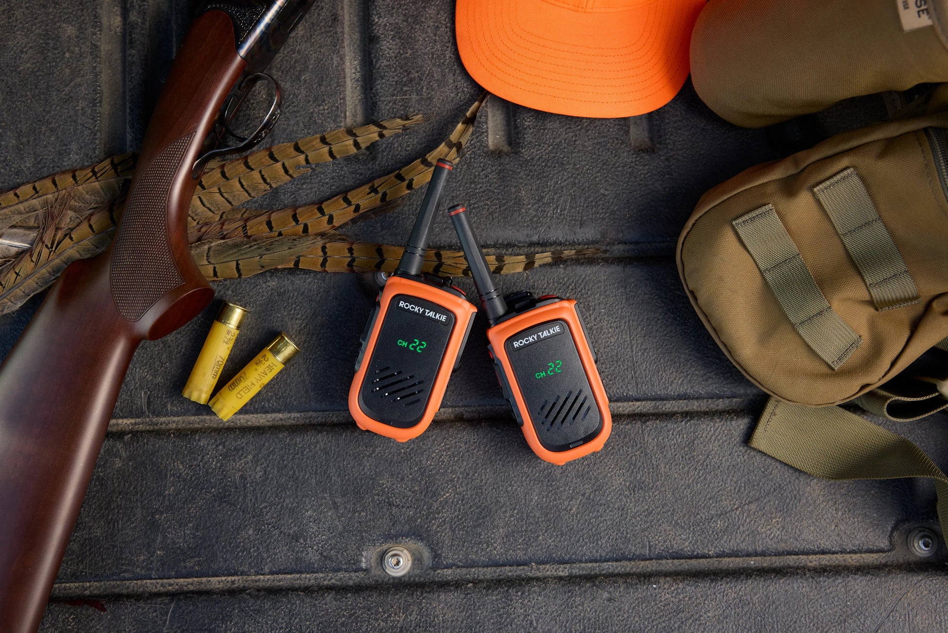 Two orange walkie-talkies with hunting equipment around.