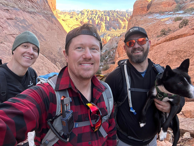 Three people with a dog taking a selfie in a desert landscape