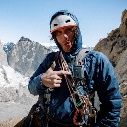 Person in climbing gear with a mountainous landscape in the background