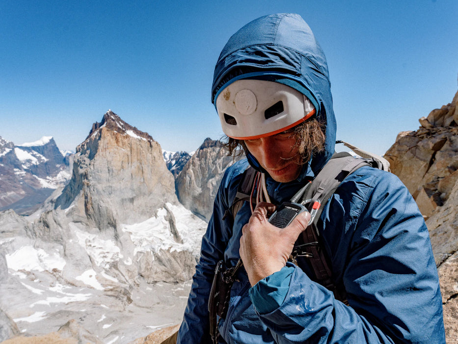 Person in blue jacket and helmet on a mountain peak
