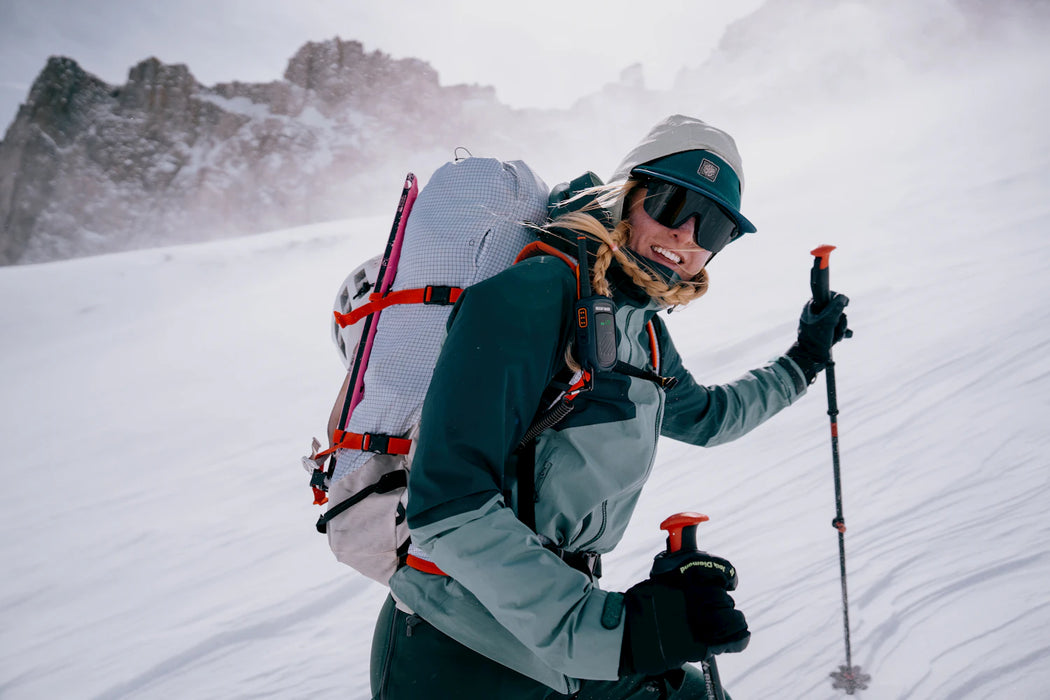 Person skiing in a snowy mountain landscape with a backpack and ski poles.
