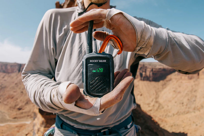 Person holding a Rocky Talkie radio in a desert landscape