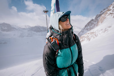 Person in winter clothing with skis on a snowy mountain