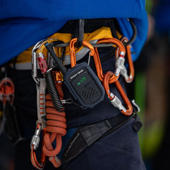 Person wearing climbing gear with orange ropes and carabiners on a blurred background