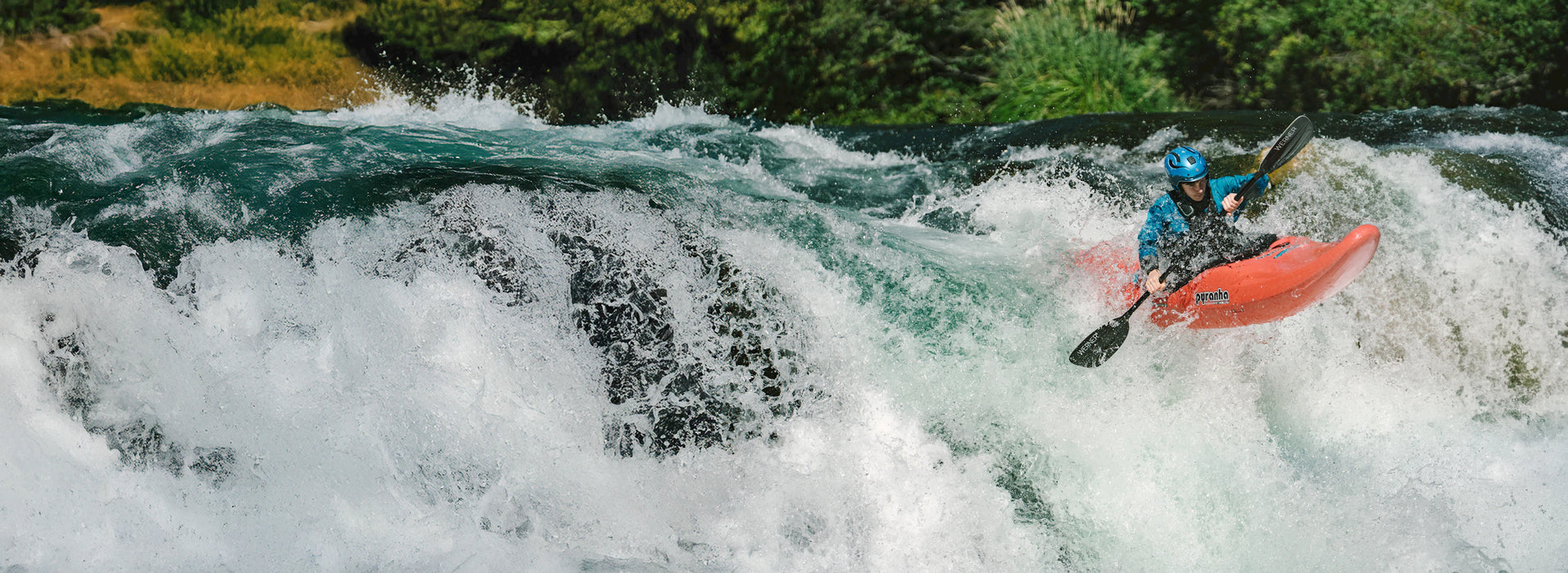 Person kayaking in turbulent water with greenery in the background