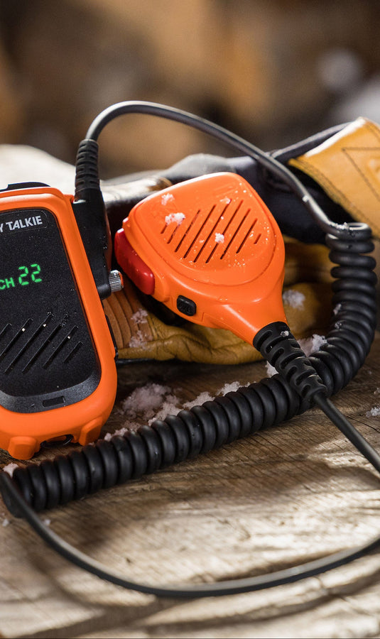 Orange walkie-talkie on a wooden surface with a blurred natural background
