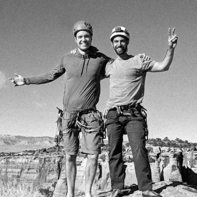 Two climbers posing on a rocky outcrop with a scenic background