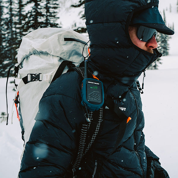 Person in winter clothing with a backpack and communication device in a snowy landscape