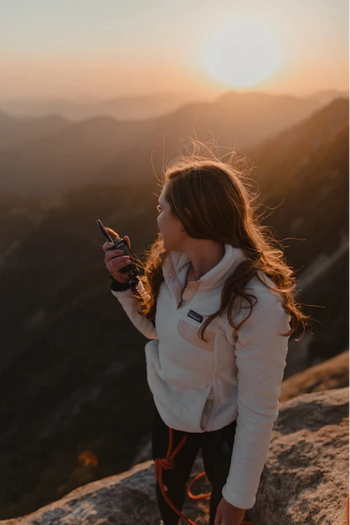 Person taking a photo of a sunset over mountains