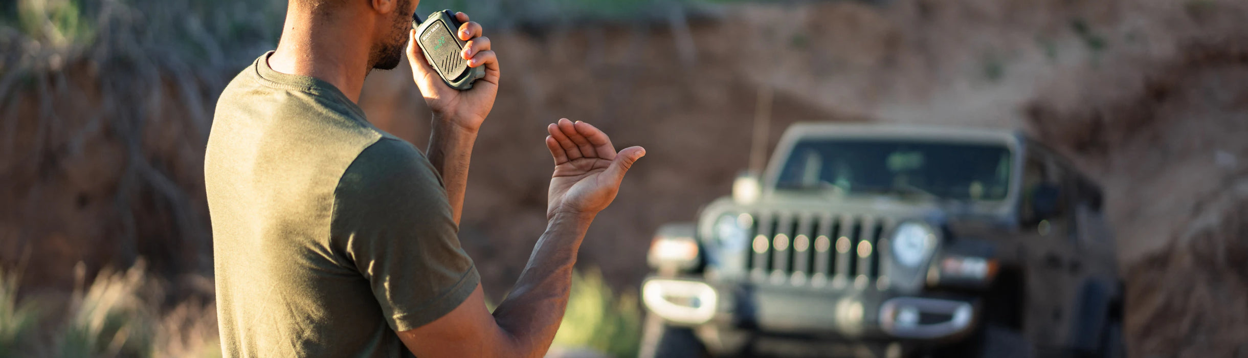 Man standing in a desert-like area with a Jeep in the background