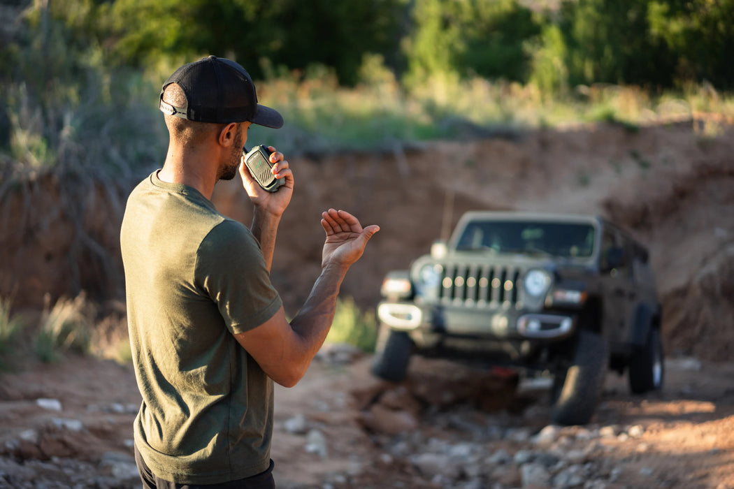 Man standing in a desert-like area with a Jeep in the background