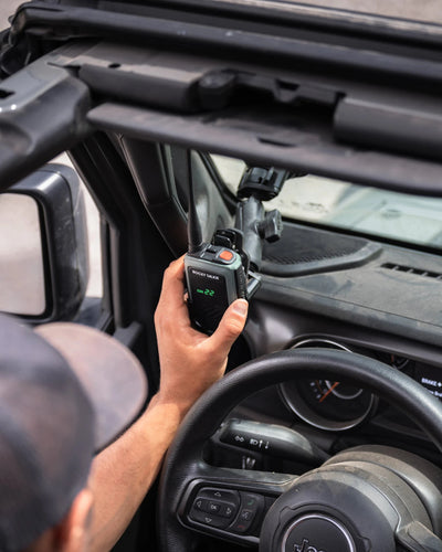 Person holding a walkie-talkie inside a vehicle