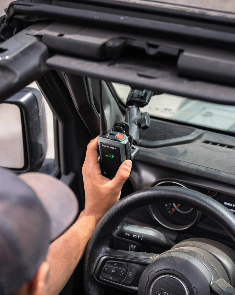 Person holding a walkie-talkie inside a vehicle