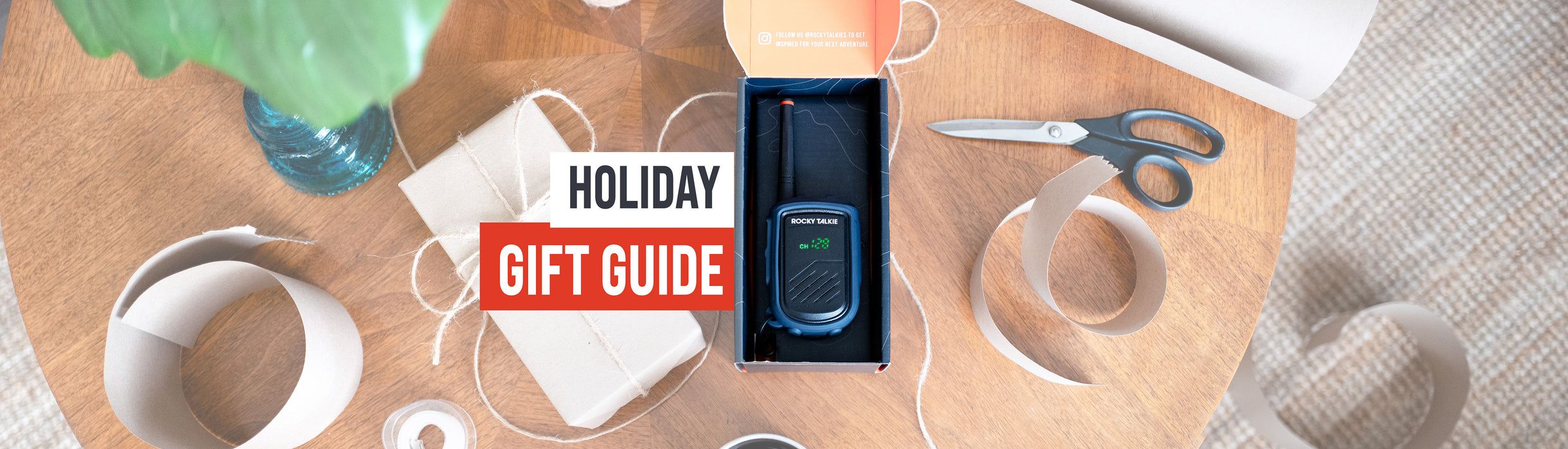 Table with office supplies and a phone box, labeled 'Holiday Gift Guide'.