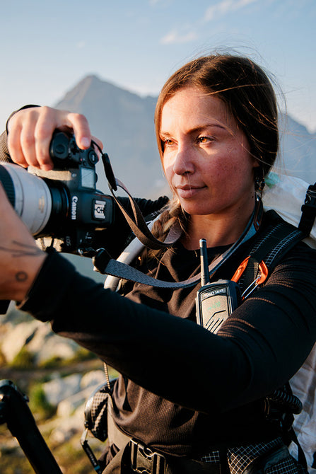 Person holding a camera with mountains in the background