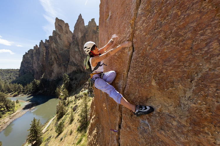 Person climbing a rocky cliff with a scenic background