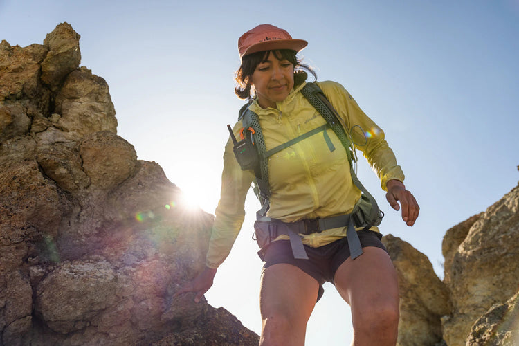 Person hiking on rocky terrain with a clear blue sky