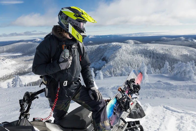 Person on a snowmobile in a snowy landscape with mountains in the background