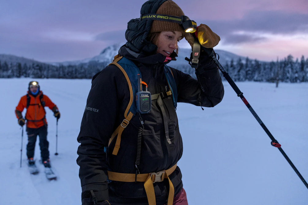 Skiers skinning across flat ground at dusk 