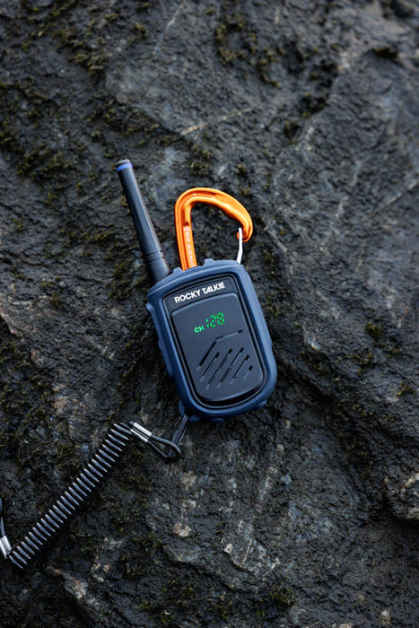 Walkie talkie with orange carabiner on a rocky surface
