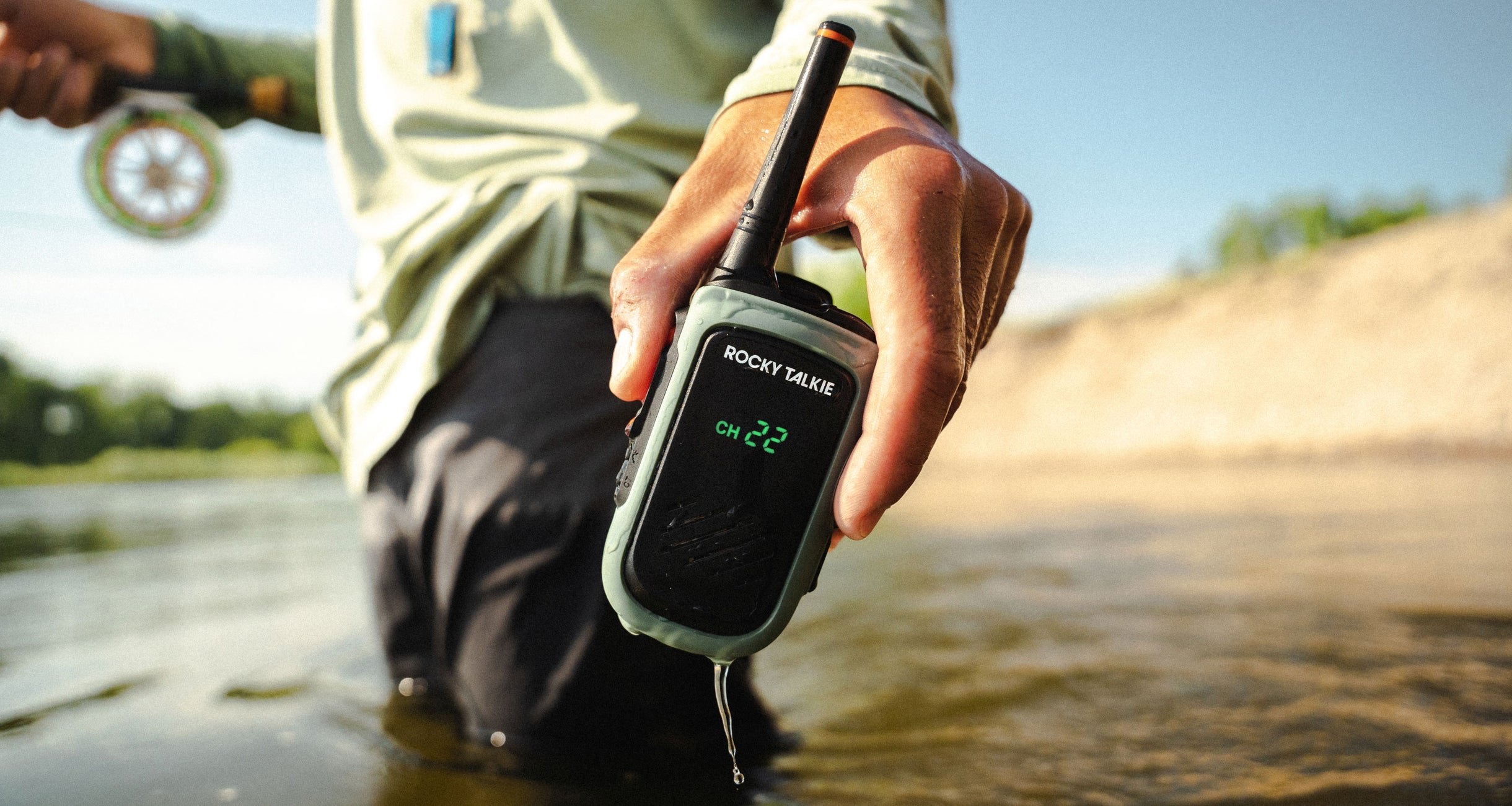 Man fishing holding a wet Expedition Radio to show that it's waterproof