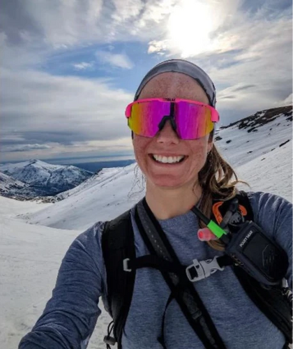 Person wearing pink goggles and a backpack on a snowy mountain