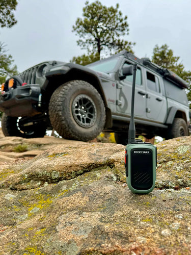 Rocky Talkie radio on a rock with off-road vehicles in the background