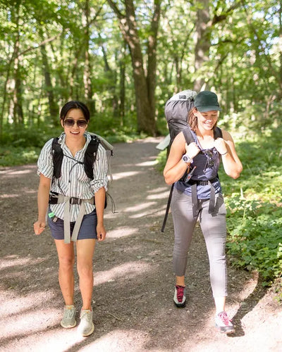 Two women hiking on a trail in a forest