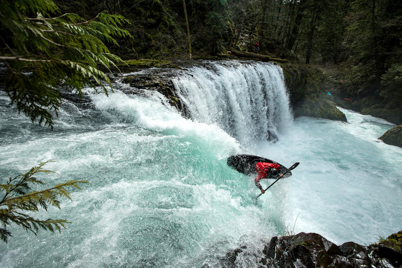 Person on a bike riding through a waterfall in a forest setting