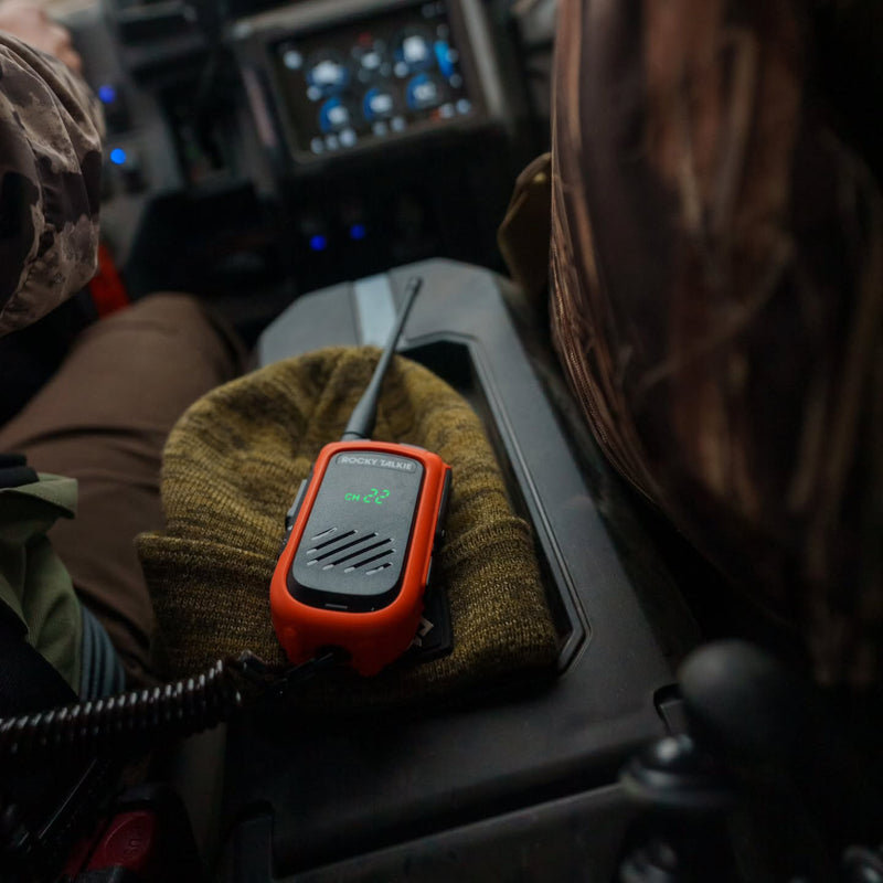 Orange walkie-talkie on a green knitted hat inside a vehicle